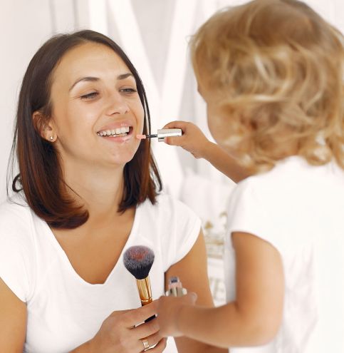 Beautiful woman with child. Woman in a white t-shirt. Mother with doughter using a cosmetics.